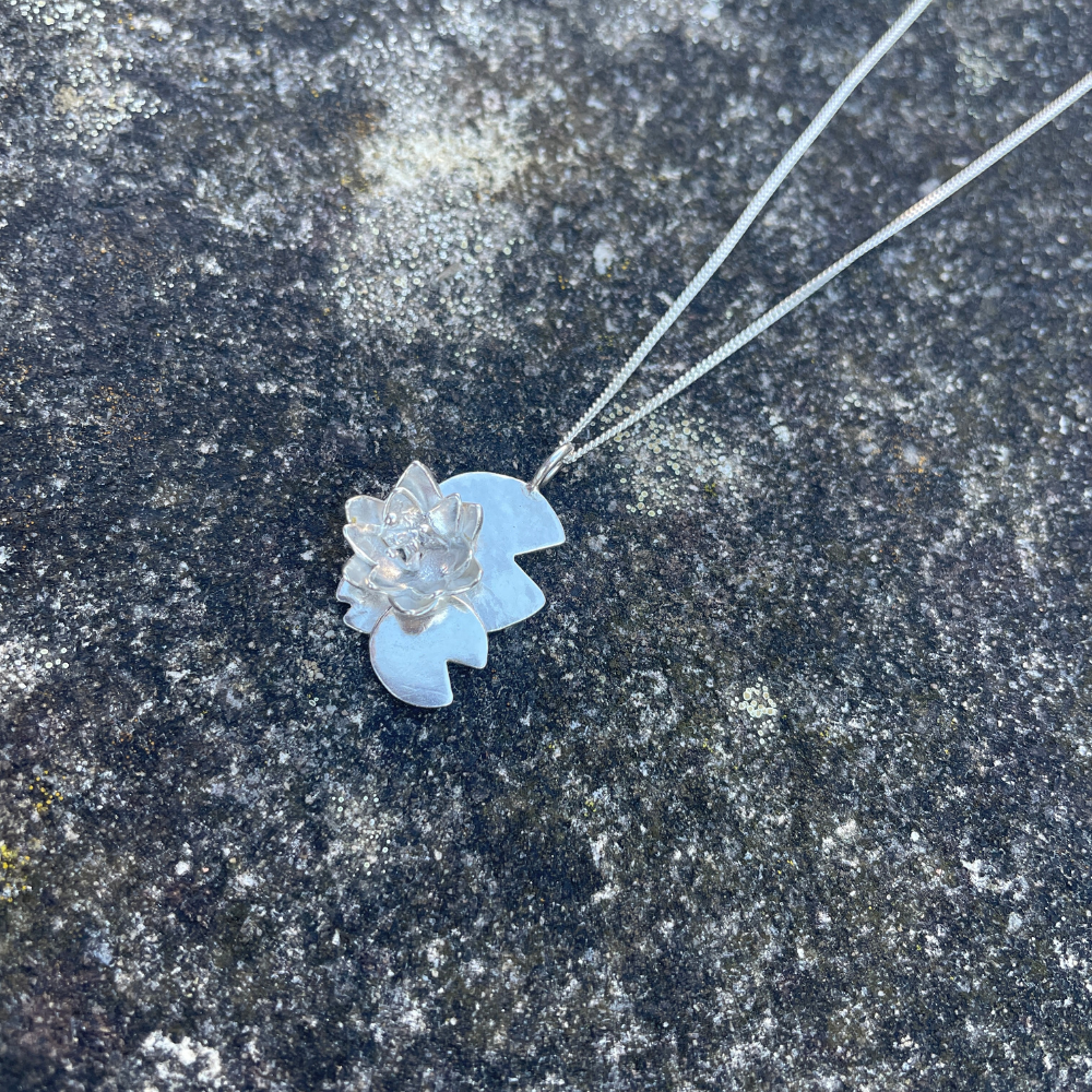 Water lily flower sat on three lily pads made from sterling silver on a curb chain handmade by Jen Lithgo Jewellery Designer