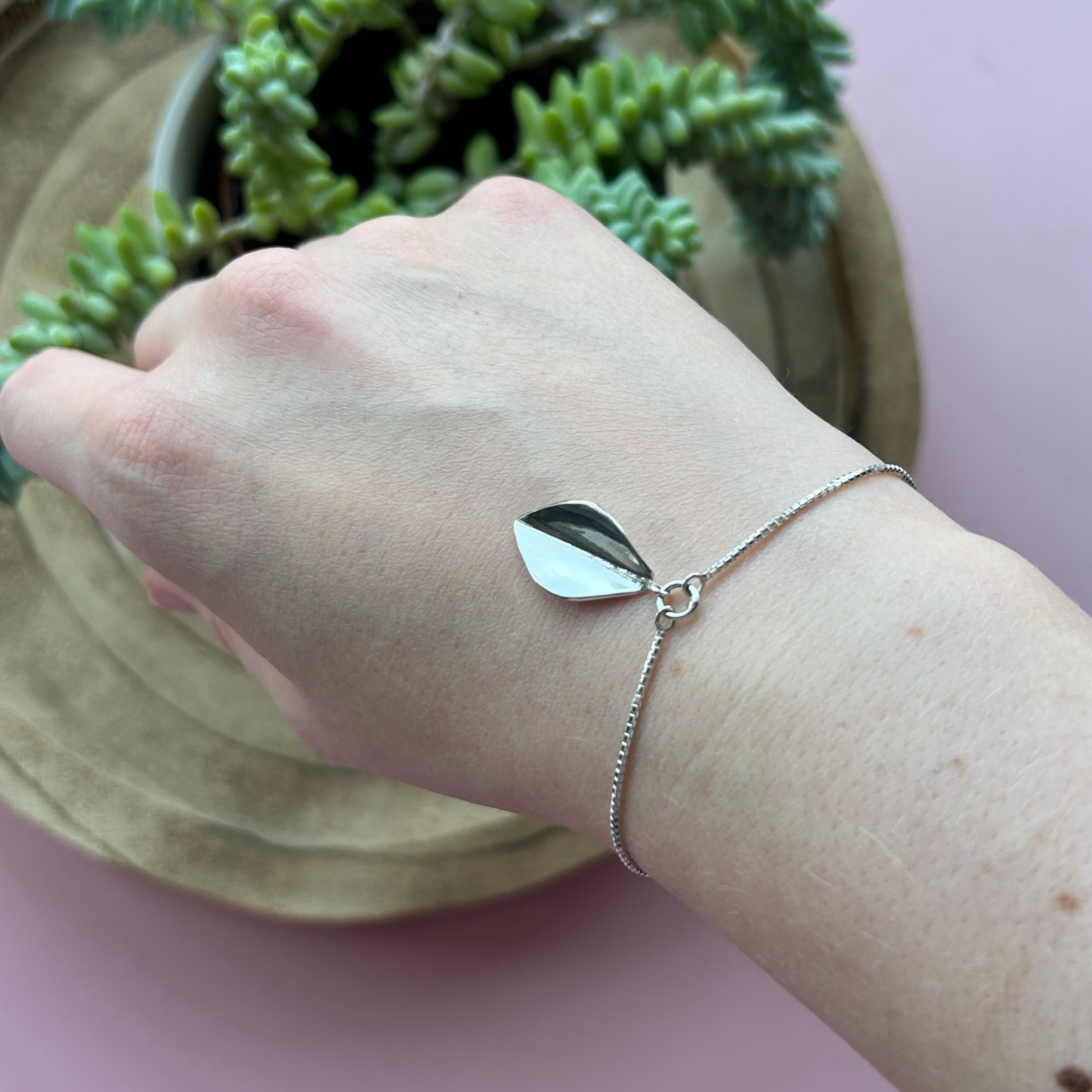 Sterling silver large leaf bracelet hanging on a box chain bracelet on a wrist. Handmade by Jen Lithgo Jewellery
