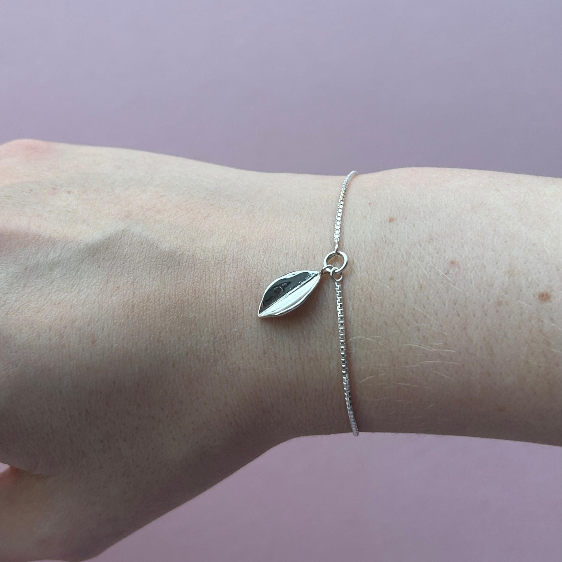 A handmade sterling silver leaf hanging on a box chain on a wrist, By Jen Lithgo Jewellery
