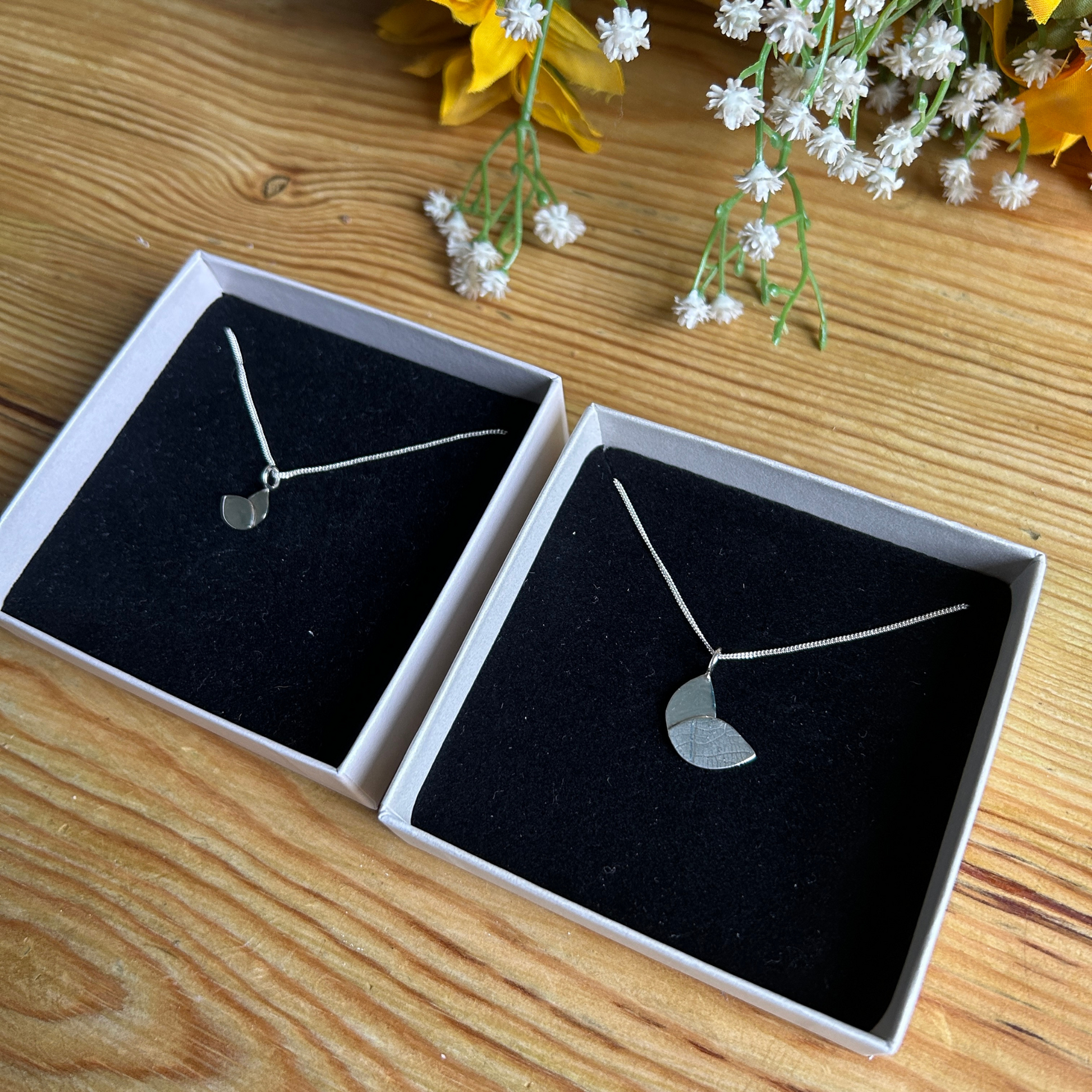 two necklaces in boxes - silver small and large duo leaf necklaces in separate boxes on wooden table top handmade by Jen Lithgo Jewellery