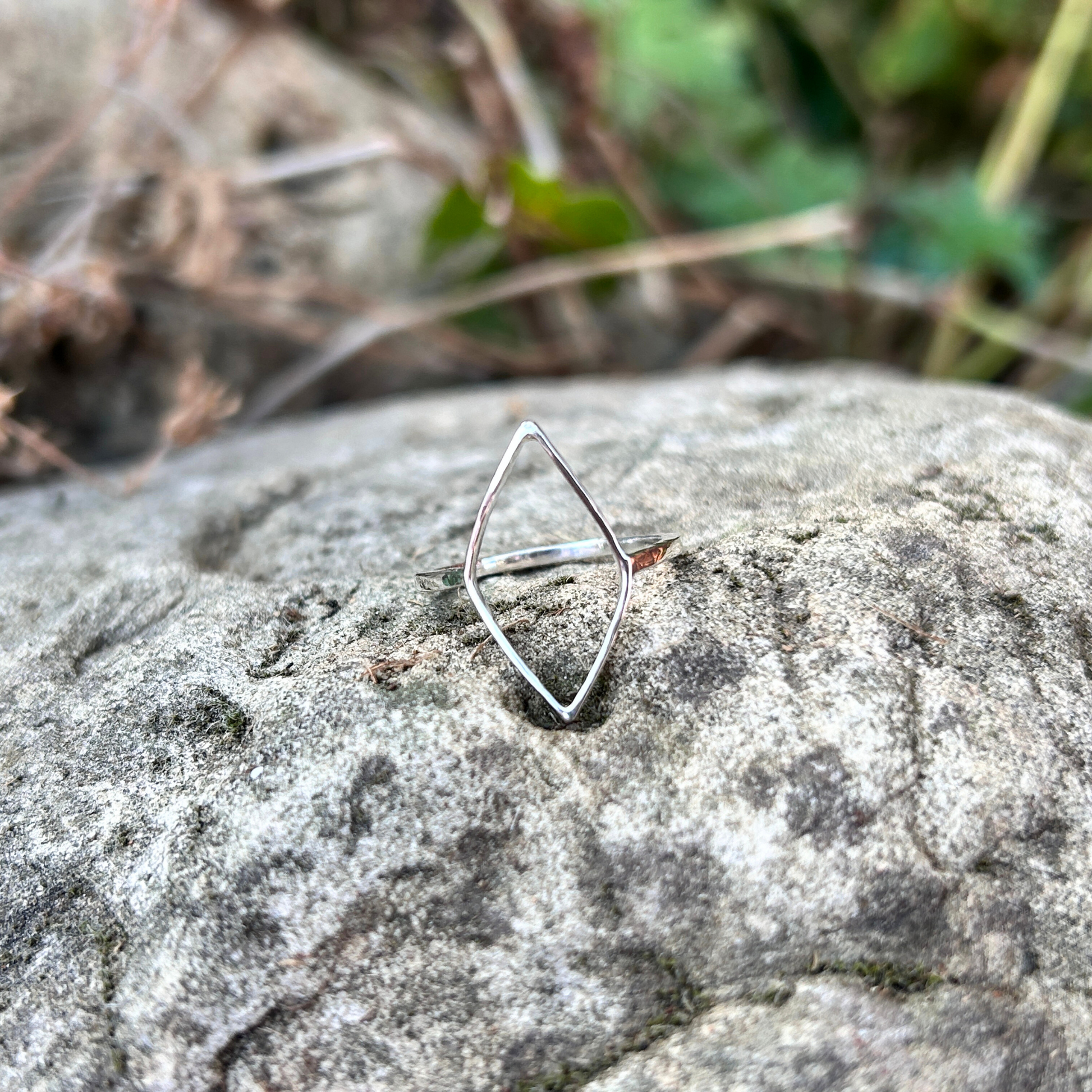 Handmade Sterling Silver geometric Leaf ring on a textured stone surface with blurred natural background