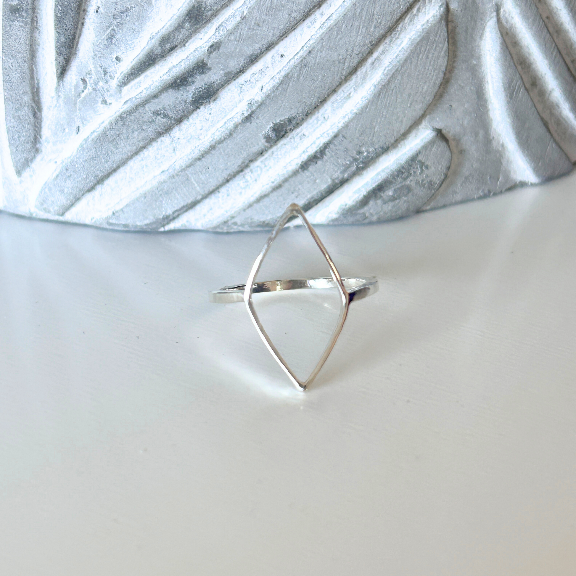 Handmade Sterling Silver geometric open leaf ring on a textured white surface