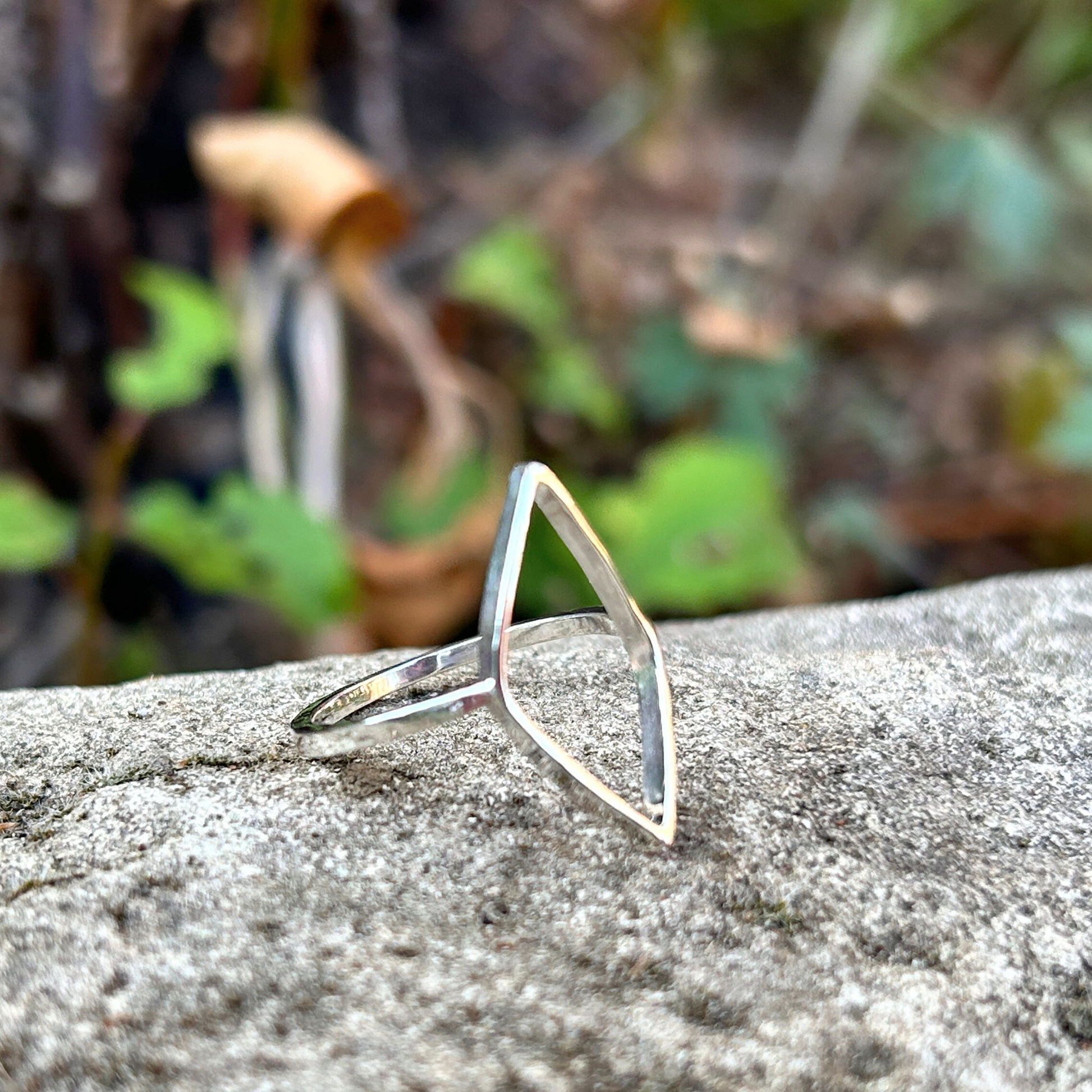 Sterling Silver open leaf ring on a textured stone surface with a blurred natural background