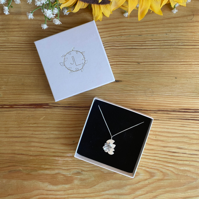 Waterlily flower and lilypad necklace in a Branded box on wooden table top. Handmade in Sterling Silver by Jen Lithgo Jewellery