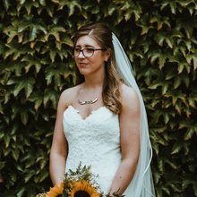 Load image into Gallery viewer, Jen wearing bridal necklace in a white wedding dress and veil infront of a leafy backdrop