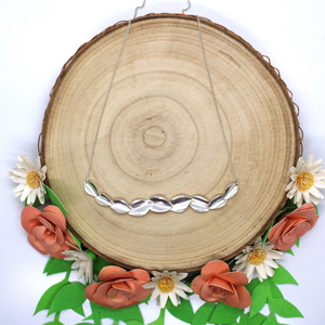 bridal necklace on log slice wrapped with paper roses and daisies