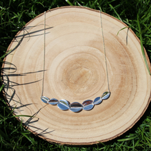 Load image into Gallery viewer, Bridesmaid 7 leaf necklace on wooden log on grass