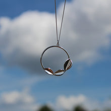 Load image into Gallery viewer, Handmade Sterling Silver Three leaves on a hoop pendant hanging on a chain held against the sky, Handmade by Jen Lithgo Jewellery