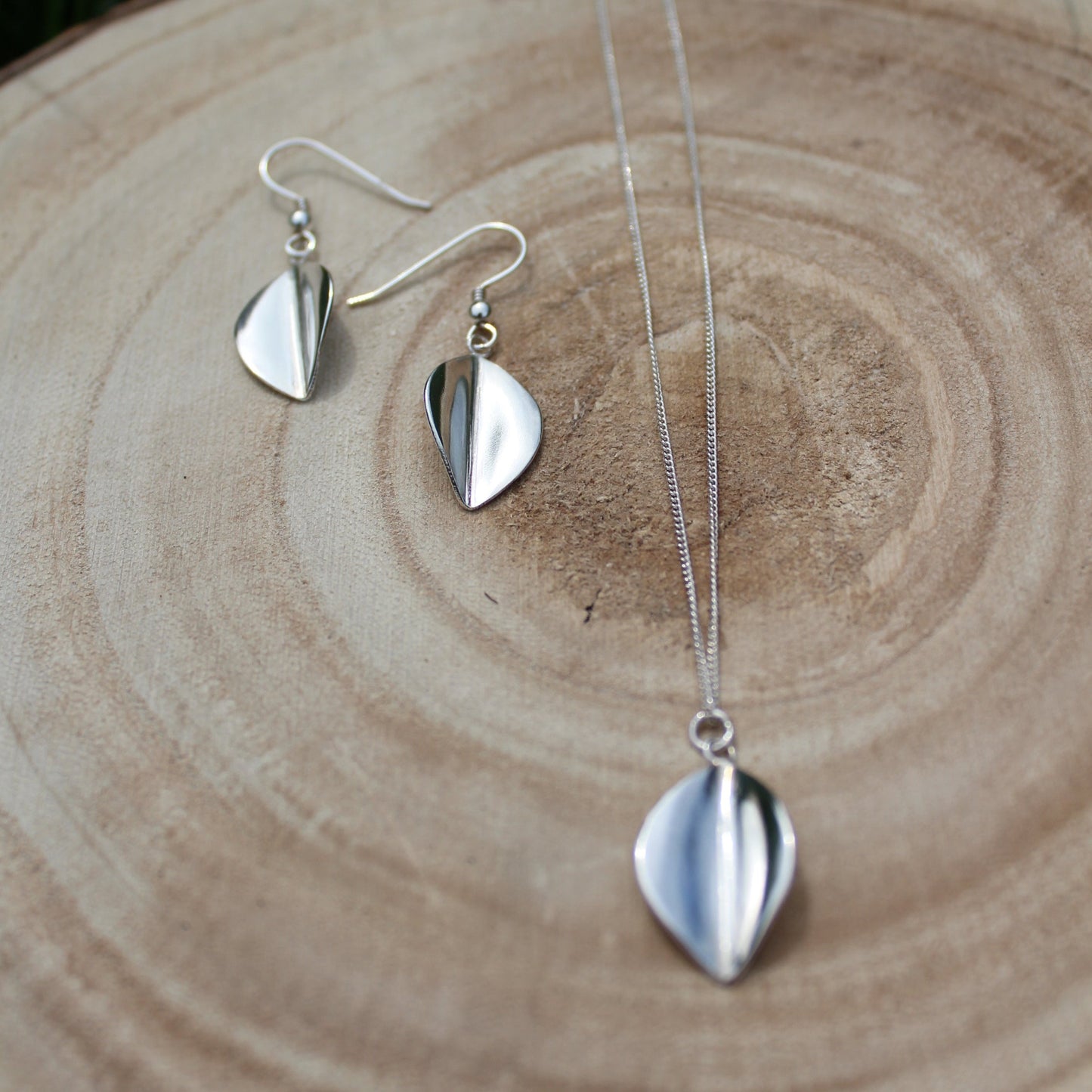 Large Leaf Drop Earrings and Necklace laid on wooden log, handmade by Jen Lithgo Jewellery