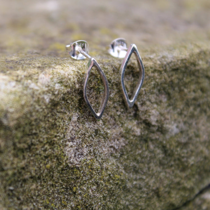 Outline Leaf Studs with scroll fastening backs sat on the edge of a rock - Handmade in Sterling Silver by Jen Lithgo Jewellery