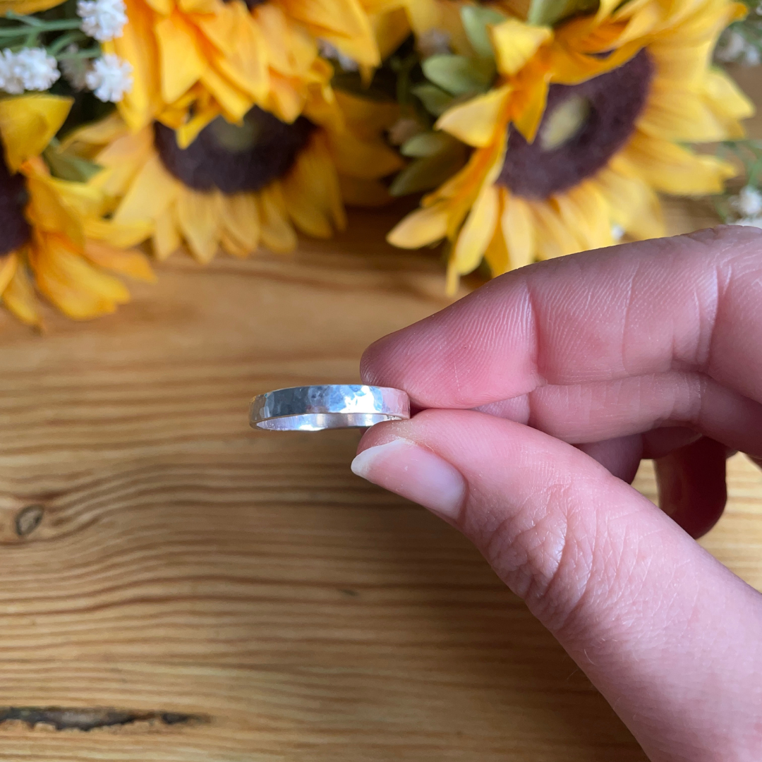 Hammered effect 4mm sterling silver ring held by ladies hand, handmade to order by Jen Lithgo Jewellery